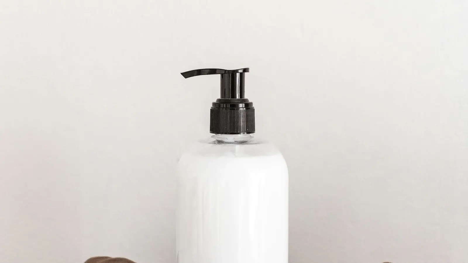 A pump-dispenser bottle, representing the asymmetric closure geometry that controls shrink-band sizing.