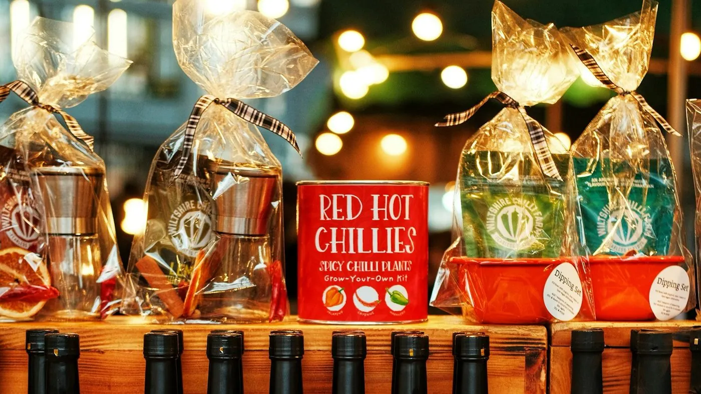 Glass bottles of chili sauce with red labels displayed on wooden crates at a market stall.